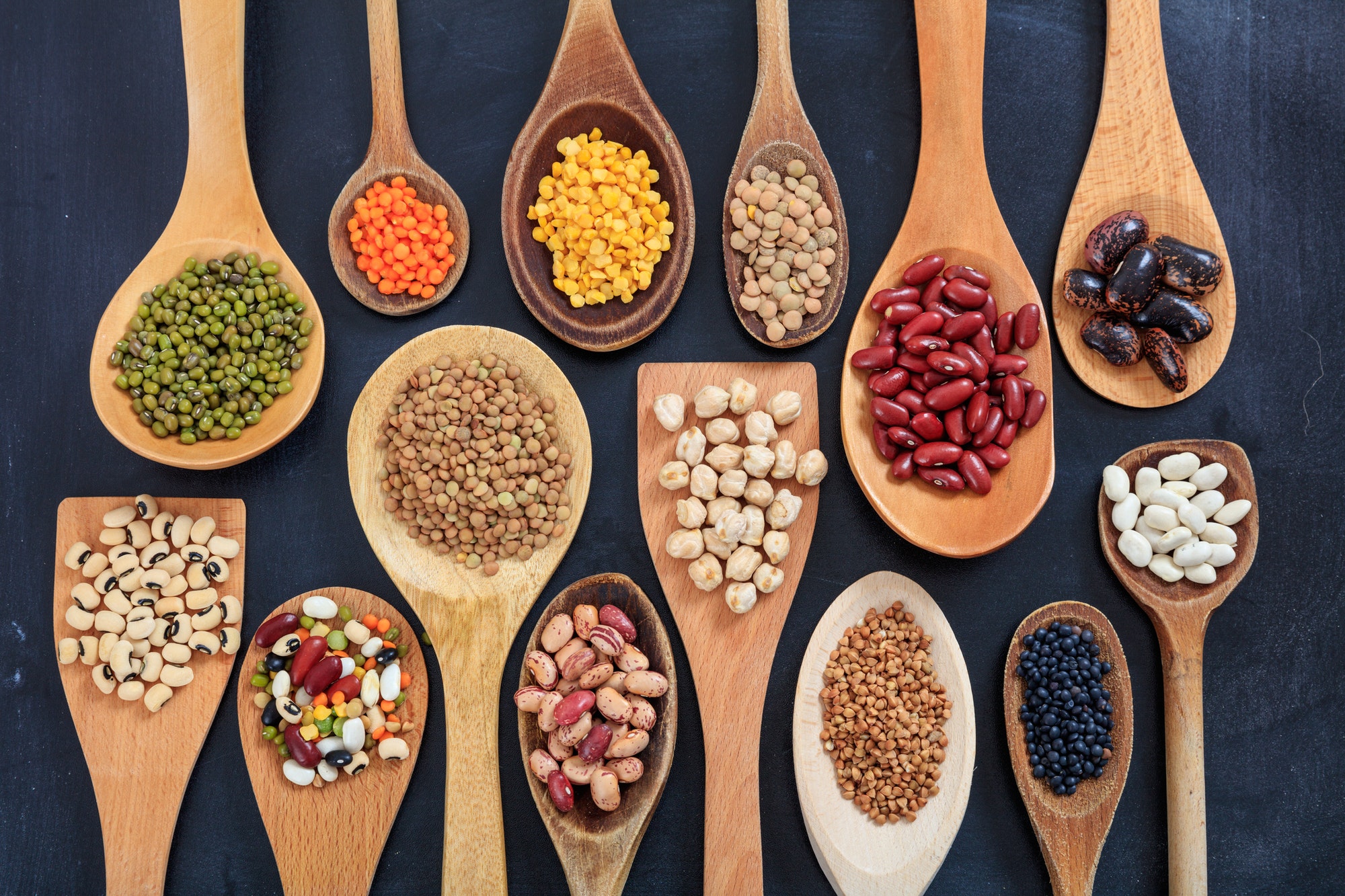 Various legumes in wooden spoons